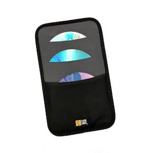 May include: A rectangular black and gray CD storage sleeve with three horizontal slots containing iridescent compact discs. The bottom section is solid black fabric with a small yellow and black Case Logic brand logo tag.