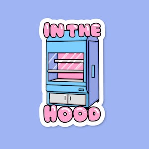 May include: A sticker showing a cartoon illustration of a blue display case with pink shelves and a white base. The text "IN THE HOOD" is written in pink bubble letters above and below the display case.