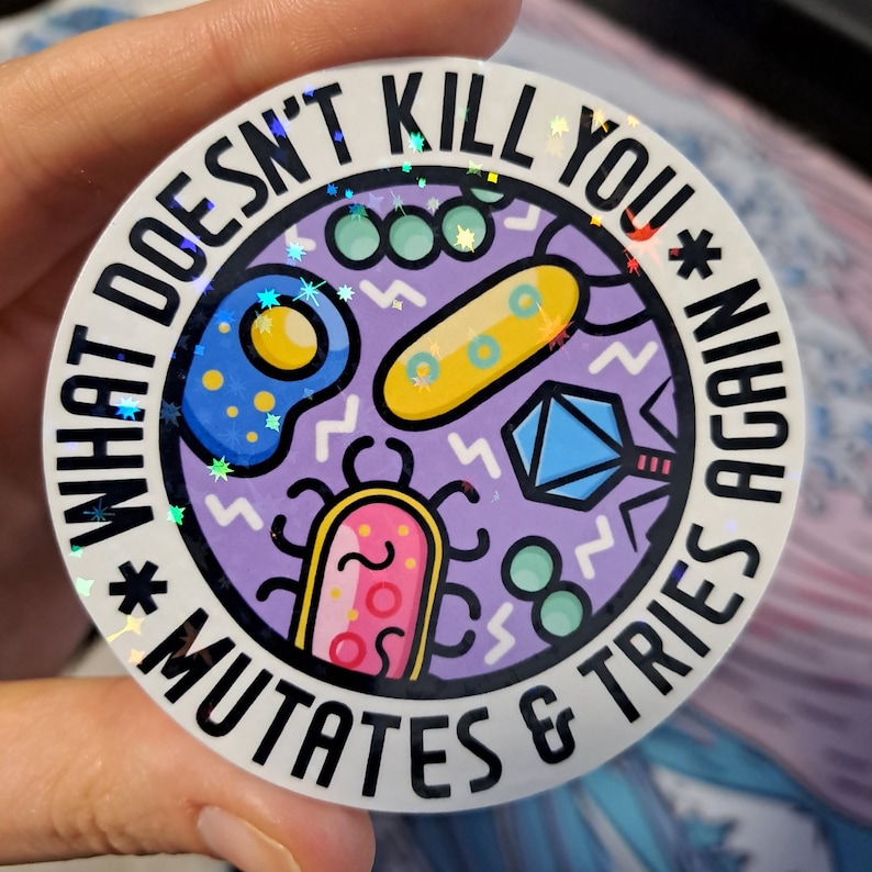 K&ouml;nnte beinhalten: Ein runder Aufkleber mit einem violetten Hintergrund und einem wei&szlig;en Rand. Der Aufkleber zeigt verschiedene bunte Cartoon-Mikroben und den Text "What doesn't kill you *mutates & tries again*" in Schwarz.