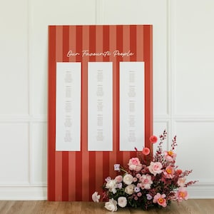 May include: A red and white striped seating chart with the text "Our Favourite People" at the top. Three white rectangular panels display guest names. A floral arrangement of pink and red flowers sits at the bottom right.