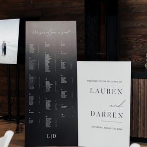 May include: Black and white wedding seating chart with the text "We saved you a seat" and "LID". A separate white sign reads "Welcome to the wedding of Lauren and Darren, Saturday, August 10, 2024".