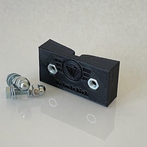 Puede incluir: Un soporte de plástico negro impreso en 3D con dos agujeros y un logotipo de diamante con el texto "Role&Schist" impreso en él. Se incluyen dos tornillos y tuercas de metal plateado.