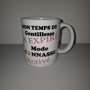 Peut inclure: Mug en céramique blanche avec du texte noir qui dit "Mon temps de gentillesse a expiré Mode connasse activé." Le texte "Mode connasse activé" est en rose. Un smiley jaune est à côté du mot "connasse".