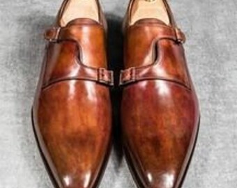 May include: A pair of brown leather monk strap shoes with a pointed toe and a polished finish.