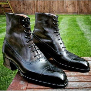 May include: A pair of black leather lace-up boots with a brogue design. The boots have a pointed toe and a low heel.