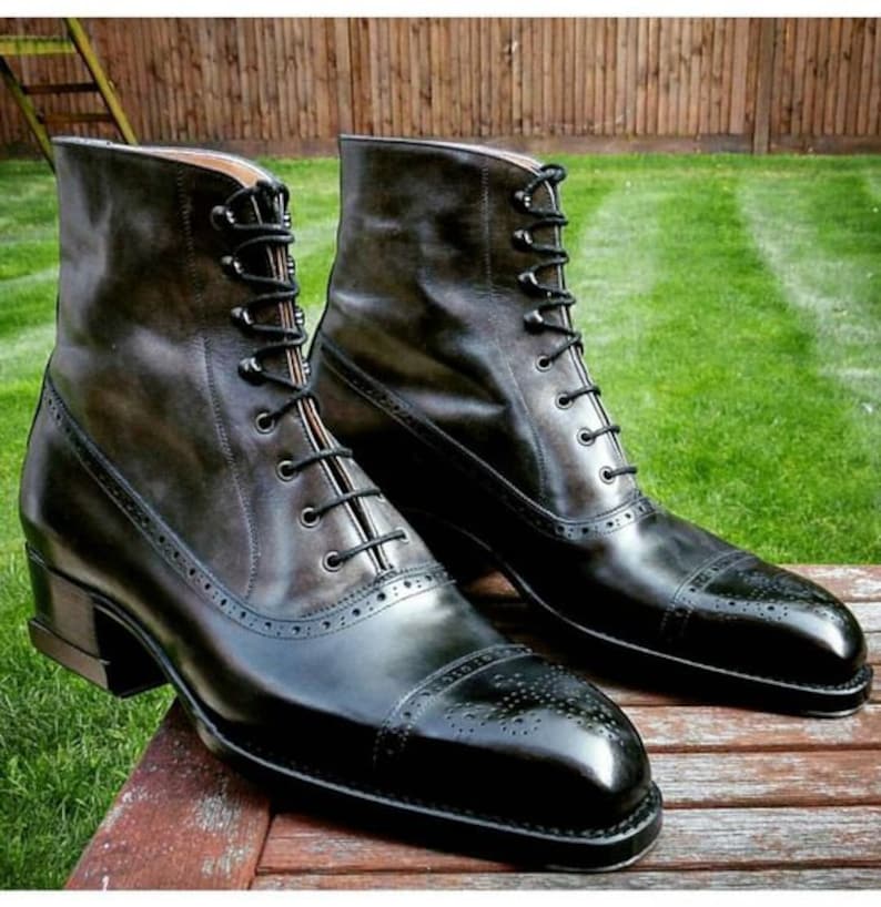 May include: A pair of black leather lace-up boots with a brogue design. The boots have a pointed toe and a low heel.