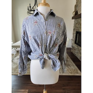 Op de afbeelding: Een overhemd met lange mouwen en knoopsluiting, voorzien van een marineblauw en wit vichy-ruitpatroon. Het overhemd is versierd met een all-over print van kleine, lichtbruine teddyberen, elk met een piepkleine rode vlinderdas. De zoom is geknoopt.