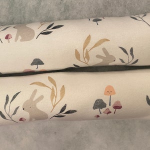 May include: Two long, rectangular pillows with a white background and a repeating pattern of brown rabbits, grey leaves, and orange mushrooms.