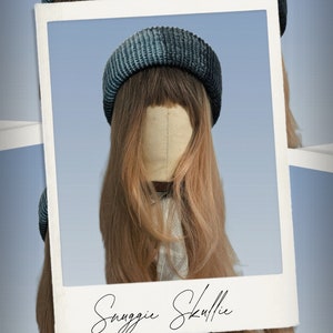 May include: A blue and grey knitted beanie hat on a mannequin head with long, light brown hair. The image is framed within a white border, with the words "Snuggie Skullie" in cursive script at the bottom.