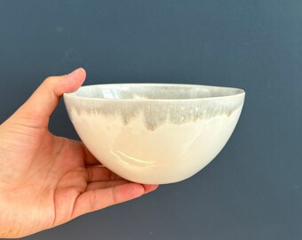 May include: A white ceramic bowl with a light gray glaze. The bowl has a rounded shape and a slightly flared rim.