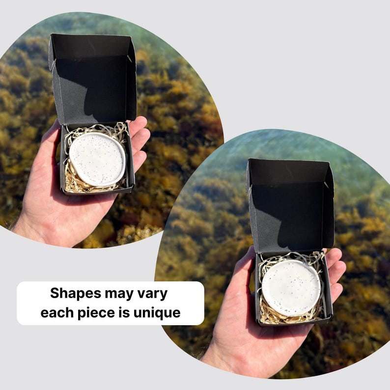 May include: A small white ceramic dish with dark speckles nestled in a black cardboard gift box filled with shredded paper filler. The text on the image reads: Shapes may vary each piece is unique. The dish has an irregular, organic circular shape.