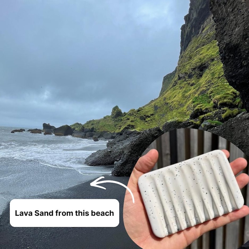 May include: A rectangular white soap dish featuring a speckled pattern of black dots and five parallel drainage grooves. The surface is smooth and the design includes a text overlay stating Lava Sand from this beach.