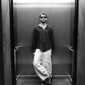 Man styling the black boho shirt with wide-leg trousers for an urban nomad look.