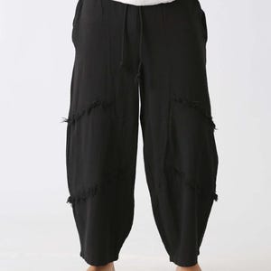 Handmade black linen palazzo pants with drawstring waist, boho harem style, distressed patches; barefoot model in white top.