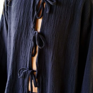 Close-up detail of Night Long Sleeve Cardigan — four delicate self-fabric bow tie closures down the deep navy cotton gauze front, showing rich textured fabric and open neckline design