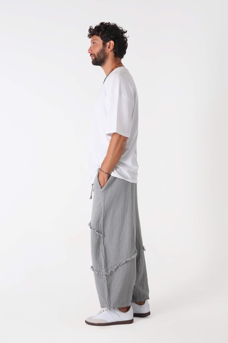 Handmade linen palazzo pants in light gray with tiered, frayed seams, worn by a male model in a white tee (boho yoga trousers).