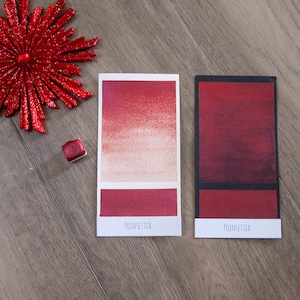 May include: Two watercolor paint swatches labeled "Poinsettia" showing a gradient of red and a solid red color.