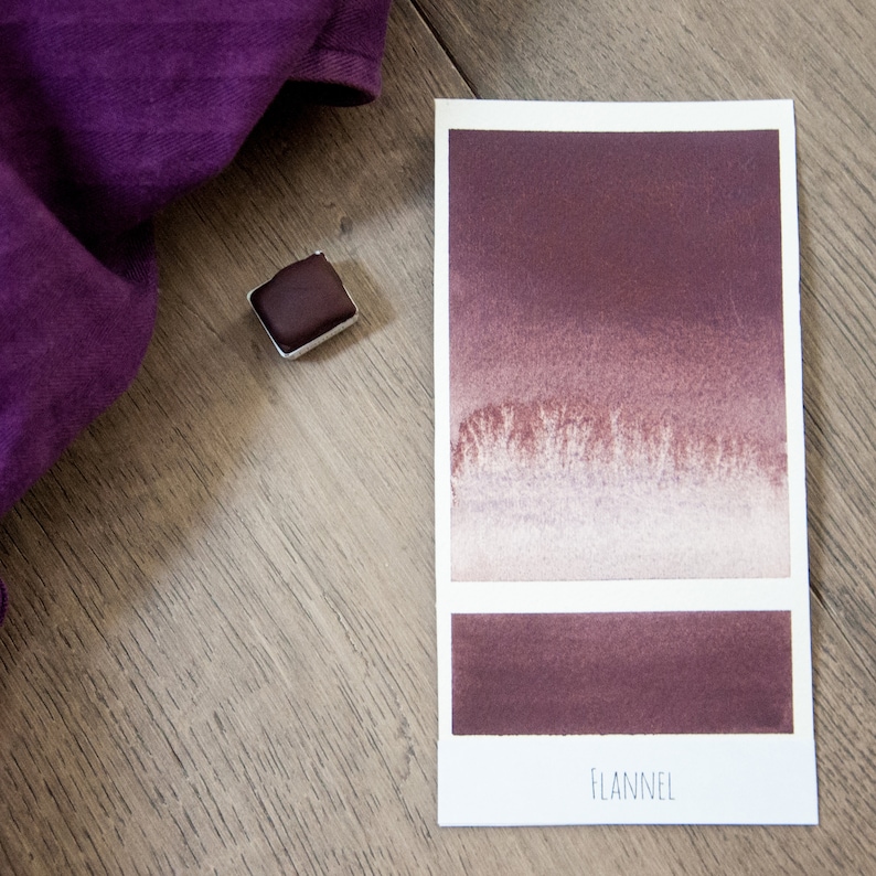 May include: A watercolor paint swatch card with a gradient of brown and white colors. The card is labeled "FLANNEL".
