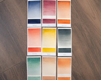 May include: Nine watercolor gradient cards with color names written below each card. The colors are:  Moonshadow, Dusk, Terra Cotta, Desert Rose,  Mousse, Cactus, Oasis, Sand, and Sun Dried.