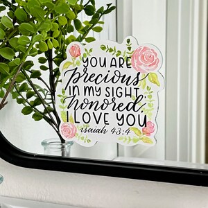 May include: A sticker with pink watercolor flowers and the text "You are precious in my sight, honored, I love you. Isaiah 43:4."