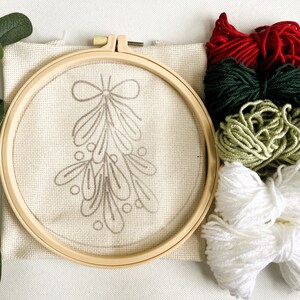 Mistletoe Punch Needle Kit showing components including pattern printed fabric, no-slip hoop and colored yarn.