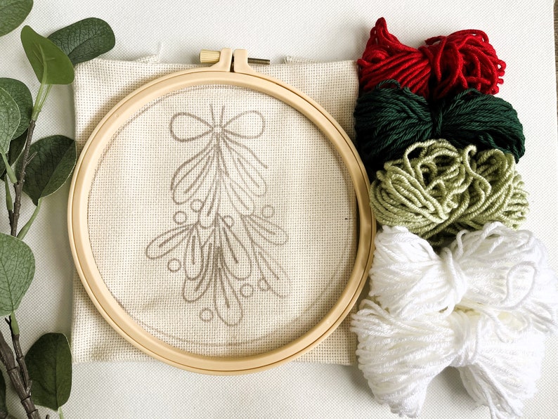 Mistletoe Punch Needle Kit showing components including pattern printed fabric, no-slip hoop and colored yarn.