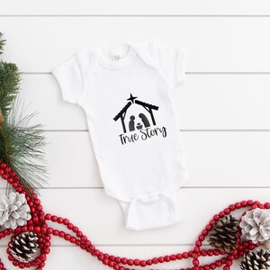May include: White baby onesie with a black silhouette of the nativity scene and the text "True Story".