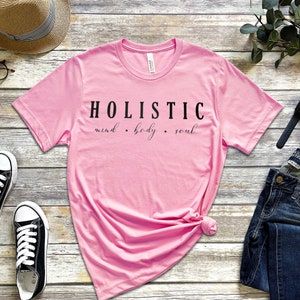 May include: Pink t-shirt with the text "HOLISTIC mind. body. soul" printed in black.