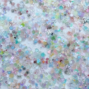 May include: A large assortment of colorful, sparkly, and translucent resin embellishments in various shapes, including hearts, stars, flowers, and bows. These embellishments are perfect for adding a touch of whimsy and sparkle to crafts, jewelry, and other projects.