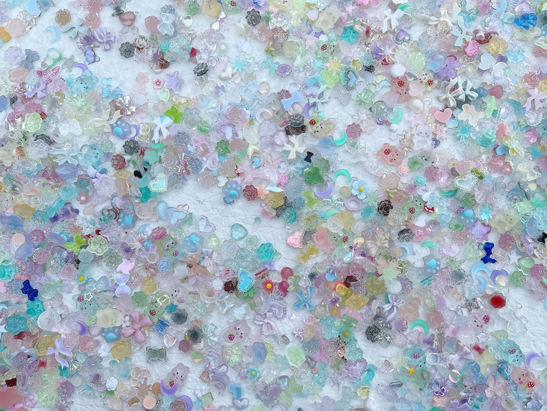 May include: A large assortment of colorful, sparkly, and translucent resin embellishments in various shapes, including hearts, stars, flowers, and bows. These embellishments are perfect for adding a touch of whimsy and sparkle to crafts, jewelry, and other projects.