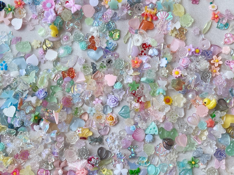 May include: A large assortment of colorful, glittery, and translucent resin charms in various shapes, including hearts, stars, butterflies, flowers, and more. These charms are perfect for adding a touch of whimsy and sparkle to crafts, jewelry, and other projects.
