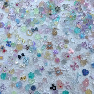May include: Assortment of colorful resin charms in various shapes, including hearts, stars, butterflies, bows, and animals. The charms are translucent and have a sparkly finish.