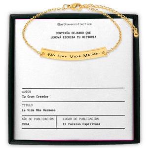 May include: A gold chain bracelet with a gold bar charm that reads "No Hay Vida Mejor." The bracelet is displayed in a black box with a white background. The box also includes the text "@arthavencollective", "CONTIN&Uacute;A DEJANDO QUE JEHOV&Aacute; ESCRIBA TU HISTORIA", "AUTOR", "Tu Gran Creador", "TITULO", "La Vida M&aacute;s Hermosa", "A&Ntilde;O DE PUBLICACI&Oacute;N", "2024", "LUGAR DE PUBLICACI&Oacute;N", and "El Para&iacute;so Espiritual."