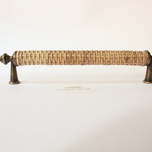 Può includere: Una maniglia per armadio in rattan intrecciato con dettagli in ottone. La maniglia è lunga circa 15 cm.