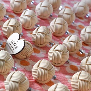 Op de afbeelding: Een verzameling beige geweven touw kastknoppen met een hartvormig houten label met de tekst "LOVE wins by HANDERCRAFT".
