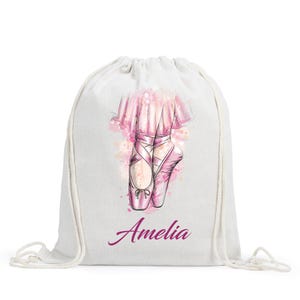 May include: White drawstring bag with a pink ballerina illustration and the name "Amelia" printed on the front.