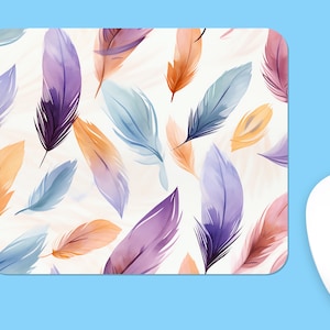 May include: A colourful mouse mat with a watercolour pattern of feathers in shades of purple, blue, and orange. The background is a light beige.