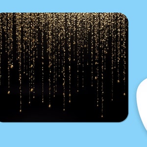 Puede incluir: Alfombrilla de ratón rectangular con fondo negro y diseño de purpurina dorada. El diseño presenta líneas verticales de purpurina dorada que parecen gotear. Un ratón de ordenador blanco está en la esquina inferior derecha de la imagen.