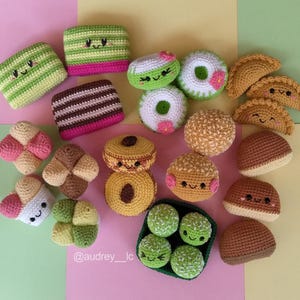 以下が含まれることがあります： さまざまなペストリー、デザート、スナックなど、かぎ針編みで作ったアミグルミの食品のコレクション。アイテムはすべて明るい色で、かわいい顔をしています。
