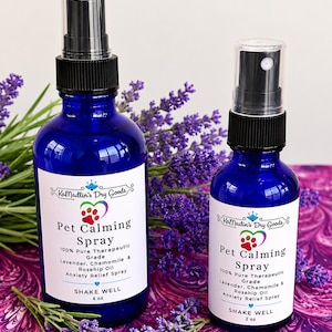 May include: Two cobalt blue glass spray bottles with black nozzles and white labels. The labels read KaMadlin's Dry Goods, Pet Calming Spray, 100% Pure Therapeutic Grade, Lavender, Chamomile & Rosehip Oil, Anxiety Relief Spray, SHAKE WELL. One bottle is 4 oz, the other is 2 oz.