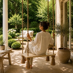 May include: A wooden swing seat suspended by thick, natural-coloured twisted rope with decorative knotted tassels at each corner. The swing features a smooth, light-toned rectangular wooden plank, providing a stable seat for outdoor relaxation.