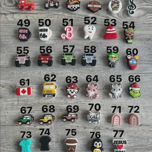 May include: A selection of decorative charms in various shapes and colours. Includes a red fire engine, a motorbike, a Hot Mama design, a Harley-Davidson logo, a coffee cup, a tooth, a Grinch, and a penguin.