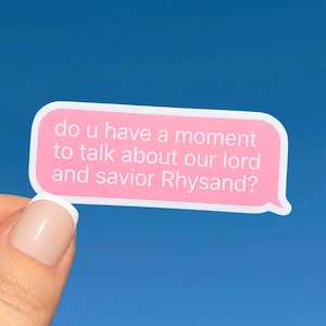 Könnte beinhalten: Ein rechteckiger rosa Aufkleber mit abgerundeten Ecken und weißem Text, der lautet: do u have a moment to talk about our lord and savior Rhysand? Der Aufkleber hat einen dünnen weißen Rand und befindet sich vor einem einfarbigen hellblauen Hintergrund.