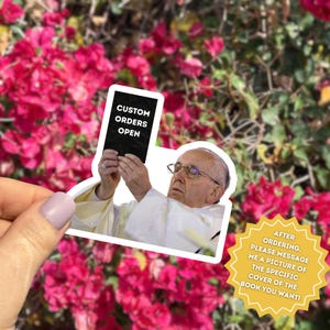 Pu&ograve; includere: Un adesivo raffigurante Papa Francesco che tiene in mano un libro con la scritta "CUSTOM ORDERS OPEN". L'adesivo &egrave; posto davanti a uno sfondo di fiori rosa. Un grafico a forma di stella gialla dice "AFTER ORDERING, PLEASE MESSAGE ME A PICTURE OF THE SPECIFIC COVER OF THE BOOK YOU WANT!"