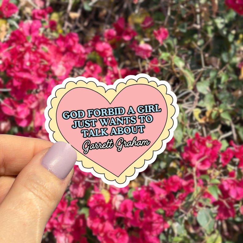 May include: A heart-shaped sticker with a pink center and a yellow scalloped border. The sticker features the text "GOD FORBID A GIRL JUST WANTS TO TALK ABOUT Garrett Graham" in a mix of fonts.
