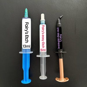 以下が含まれることがあります： 白いラベルと黒い文字の3つの注射器。最初のものは青色で「Fairy's Etch 13ml」と書かれています。2番目のものは透明で「Fairy's easy Etch 5ml」と書かれています。3番目のものは黒色で「Fairy's one step adhesive」と書かれています。