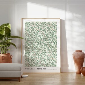 Puede incluir: Una impresi&oacute;n enmarcada de un patr&oacute;n floral verde y blanco con el texto "WILLIAM MORRIS Willow Bough, 1887". La impresi&oacute;n est&aacute; colgada en una pared blanca en una habitaci&oacute;n con una planta en maceta y dos jarrones de terracota.