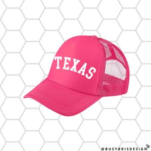 May include: Pink trucker hat with a white mesh back and the word "TEXAS" in white letters on the front.