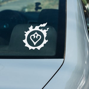 May include: A white vinyl sticker of the Final Fantasy XIV logo on the back window of a silver car.