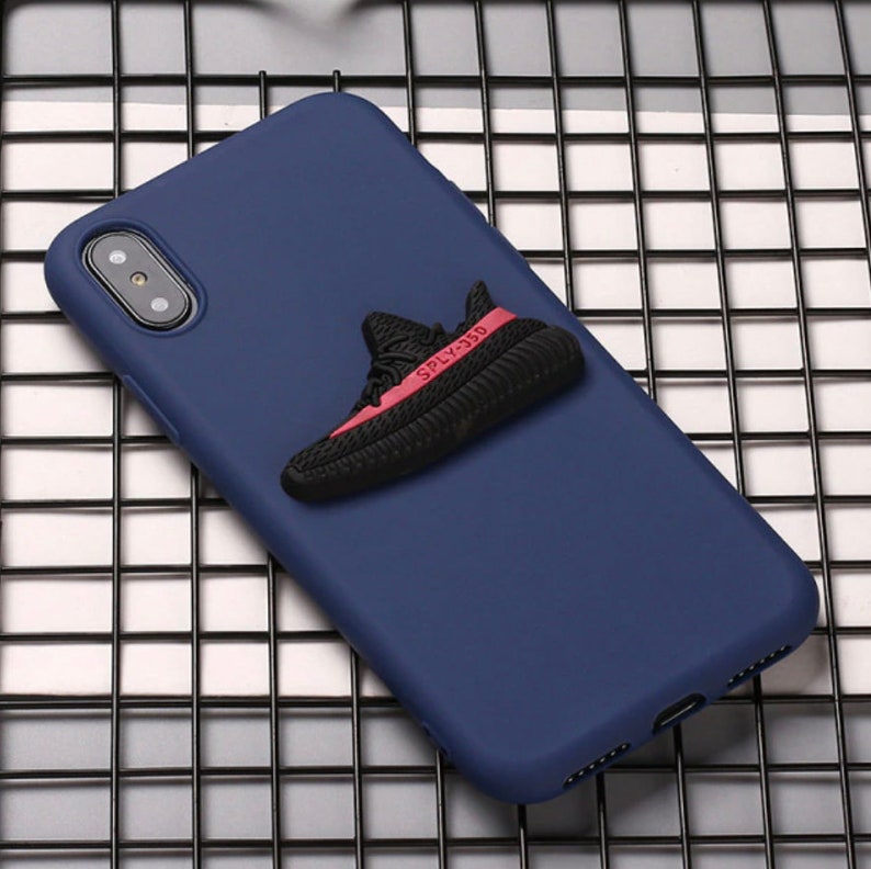 Puede incluir: Una funda de tel&eacute;fono azul marino con un dise&ntilde;o de zapato 3D en negro y rojo. El zapato tiene el texto "SPLY-350" en el lateral.